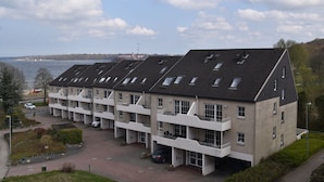 A multi-story building with a flat roof, large windows, and a view of the water. - fewo1846 - Fördeblick I (App. 670) / Studio apartment with balcony on the mezzanine floor (Harrislee)