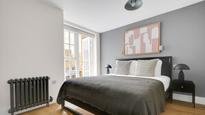 Ein Schlafzimmer mit Bett, Nachttischen, Heizkörper und Fenster.