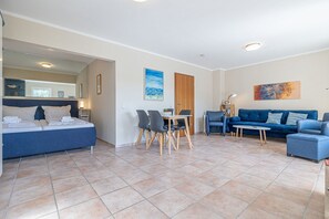 Une chambre d’hôtel moderne avec un lit, un canapé bleu, une table à manger avec des chaises et une petite table basse.