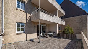 A two-story building with a balcony, outdoor seating area, and a gravel patio. - fewo1846 - Fördeblick II (Apartment 671) Studio apartment with a terrace on the mezzanine level (Harrislee)