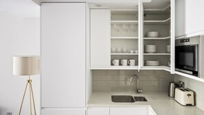 A modern kitchen with white cabinetry, a built-in oven, a sink, and a toaster. - Open plan Waterloo, 2BR, New build, terrace, by Blueground (London)