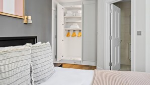 A bedroom with a bed, a wardrobe, and a bathroom visible through an open door. - Open plan Waterloo, 2BR, New build, terrace, by Blueground (London)