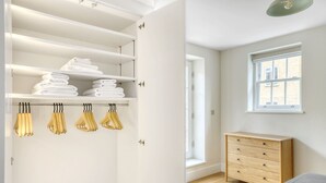 A room with a wooden dresser, a window with a view, and a closet with shelves and hanging items. - Open plan Waterloo, 1BR, New build, terrace, by Blueground (London)