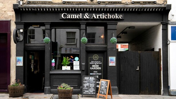 A black storefront with the sign "Camel & Artichoke" and a signboard advertising daily deals. - Open plan Waterloo, 1BR, New build, terrace, by Blueground (London)
