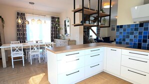 Una cocina moderna con armarios blancos, encimera de madera e iluminación colgante.