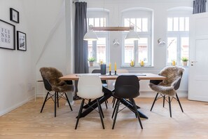 Ein Essbereich mit einem Holztisch, vier Stühlen und Pendelleuchten.
