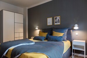 Ein Schlafzimmer mit Bett, Nachttischen, einem Kleiderschrank und Wandleuchten.