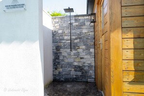 Un espace de douche en pierre avec une porte en bois et un panneau indiquant qu’il est réservé aux douches.