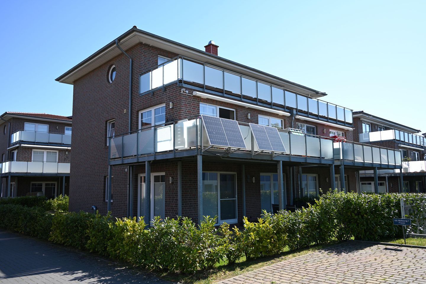 A modern two-story building with a flat roof, solar panels, and a covered outdoor area.