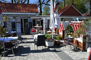 Ein Straßencafé mit Tischen und Stühlen, einer Kaffeestation und einem Schild mit der Aufschrift 'Hafencafe'.