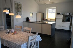 Eine moderne Küche mit Kochinsel, weißen Schränken und einem Essbereich mit gemustertem Tischlein.