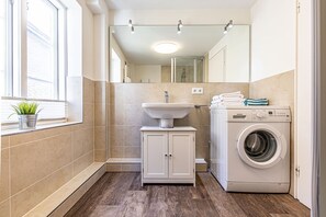 Un baño pequeño con lavamanos, espejo y lavadora.
