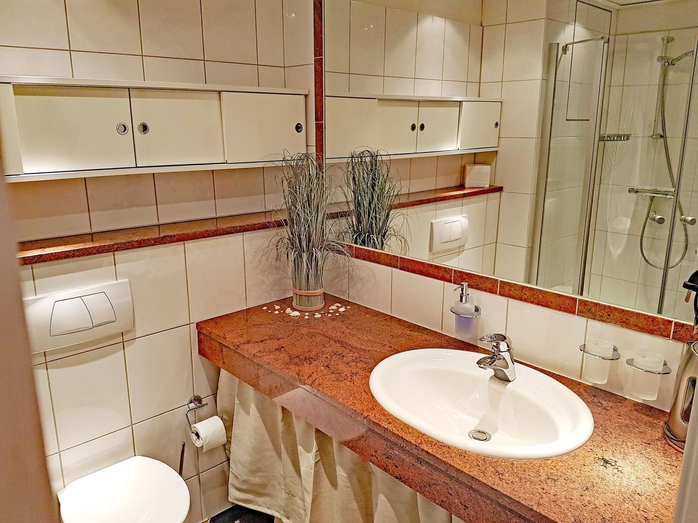 Un baño con un lavamanos blanco, un espejo, una ducha y un inodoro.