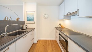 A compact kitchen with a sink, stove, and cabinets. - fewo1846 - Lina K. (App. 504) elegant StudioApartment- sea view up to 4 Per. (Glücksburg (Ostsee))