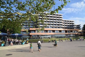 A spacious outdoor area with a modern building in the background, featuring multiple balconies and large windows. - fewo1846 - Lina K. (App. 504) elegant StudioApartment- sea view up to 4 Per. (Glücksburg (Ostsee))