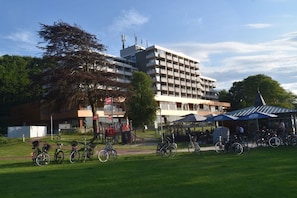 Ein mehrstöckiges Gebäude mit modernem Design, einer überdachten Außenbereich-Sitzgelegenheit und einem Fahrradstellplatz.