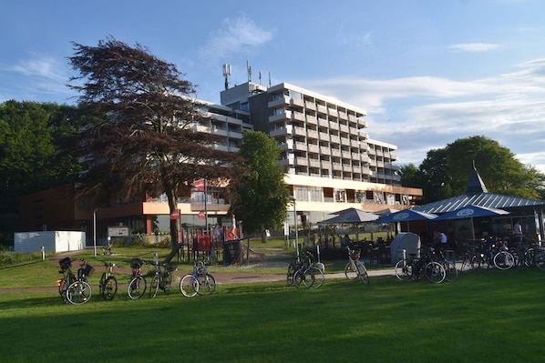 Ein mehrstöckiges Gebäude mit modernem Design, einer überdachten Außenbereich-Sitzgelegenheit und einem Fahrradstellplatz.