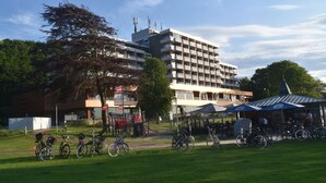 A multi-story building with a modern design, a covered outdoor seating area, and a bicycle parking area. - fewo1846 - At the Beach - elegant studio apartment with balcony and sea view - (Glücksburg (Ostsee))