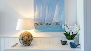 A wall-mounted painting of sailboats, a lamp, and a plant arrangement. - fewo1846 - At the Beach - elegant studio apartment with balcony and sea view - (Glücksburg (Ostsee))