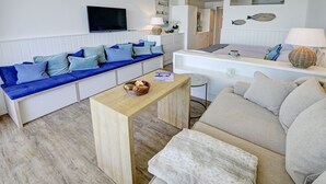 A modern living room with a blue sofa, a beige sofa, and a wooden coffee table. - fewo1846 - Rooftop (App. 604) elegant studio apartment with balcony and sea view (Glücksburg (Ostsee))