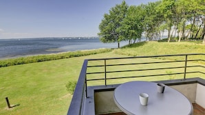 A balcony with a table and chairs, overlooking a grassy area and a body of water with sailboats. - fewo1846 - Fjordview (App. 18) - fewo1846 - Fjordview / modern studio apartment (Glücksburg (Ostsee))