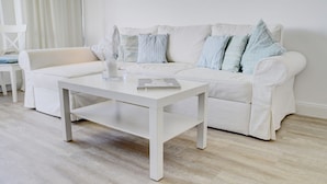 A modern living room with a white sofa, a white coffee table, and a glass candle holder. - fewo1846 - Fjordview (App. 18) - fewo1846 - Fjordview / modern studio apartment (Glücksburg (Ostsee))
