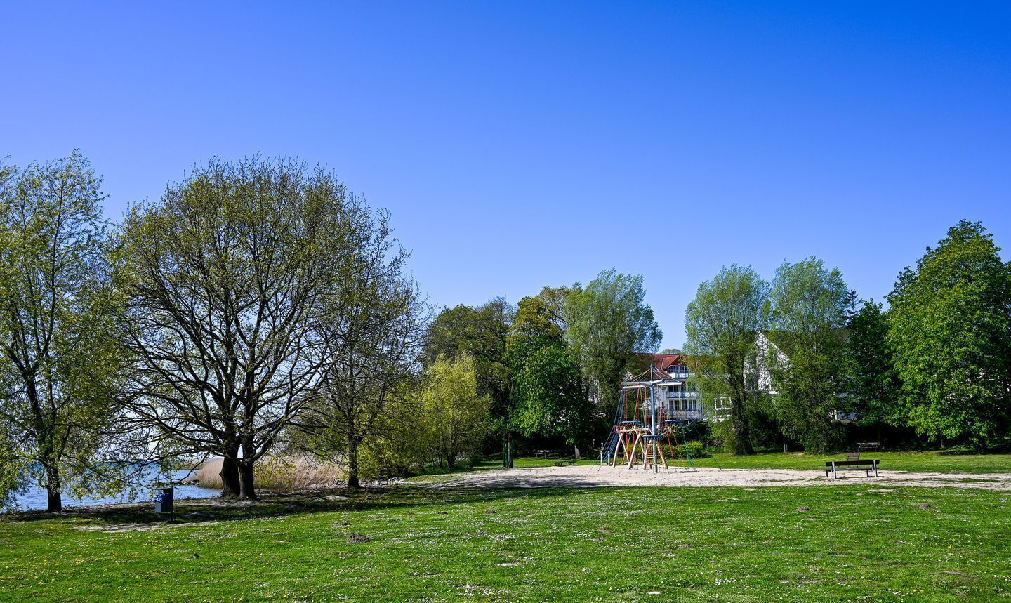 A park with a playground, a bench, and a building in the background.
