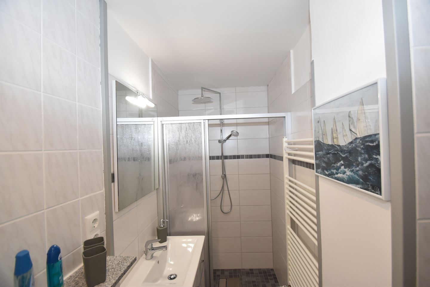 A bathroom with a shower, a sink, and a towel rack.