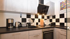 A modern kitchen with a black and white checkered backsplash, stainless steel appliances, and a built-in oven. - fewo1846 - Pauline - fewo1846 - Pauline in Glücksburg / enchanting (Glücksburg (Ostsee))