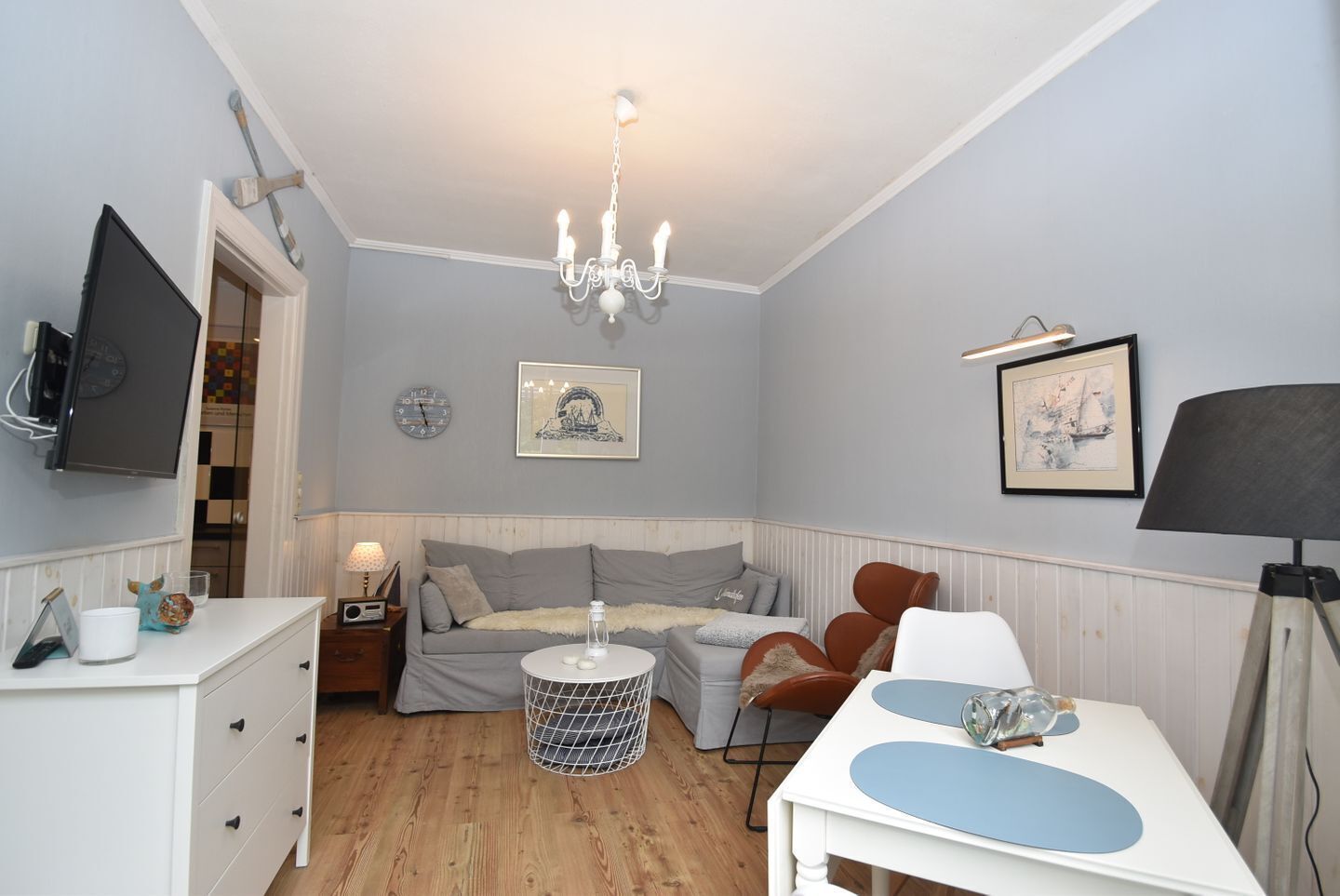 A cozy bedroom with a bed, bedside table, lamp, and a chandelier.