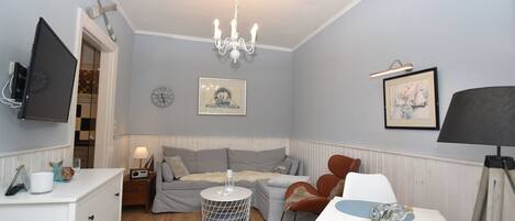 A cozy bedroom with a bed, bedside table, lamp, and a chandelier.
