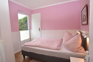 A bedroom with a bed, a window, and a door.