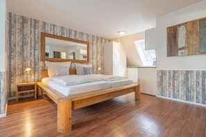 Une chambre à coucher avec un lit en bois, une table de chevet, un grand miroir et une fenêtre donnant sur un beau paysage.