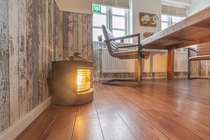 A room with a rustic wooden wall, a modern chair, and a heater on the floor.