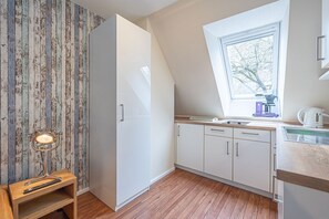 Eine kleine Küche mit Fenster, Holzboden und einem eingebauten Schrank.