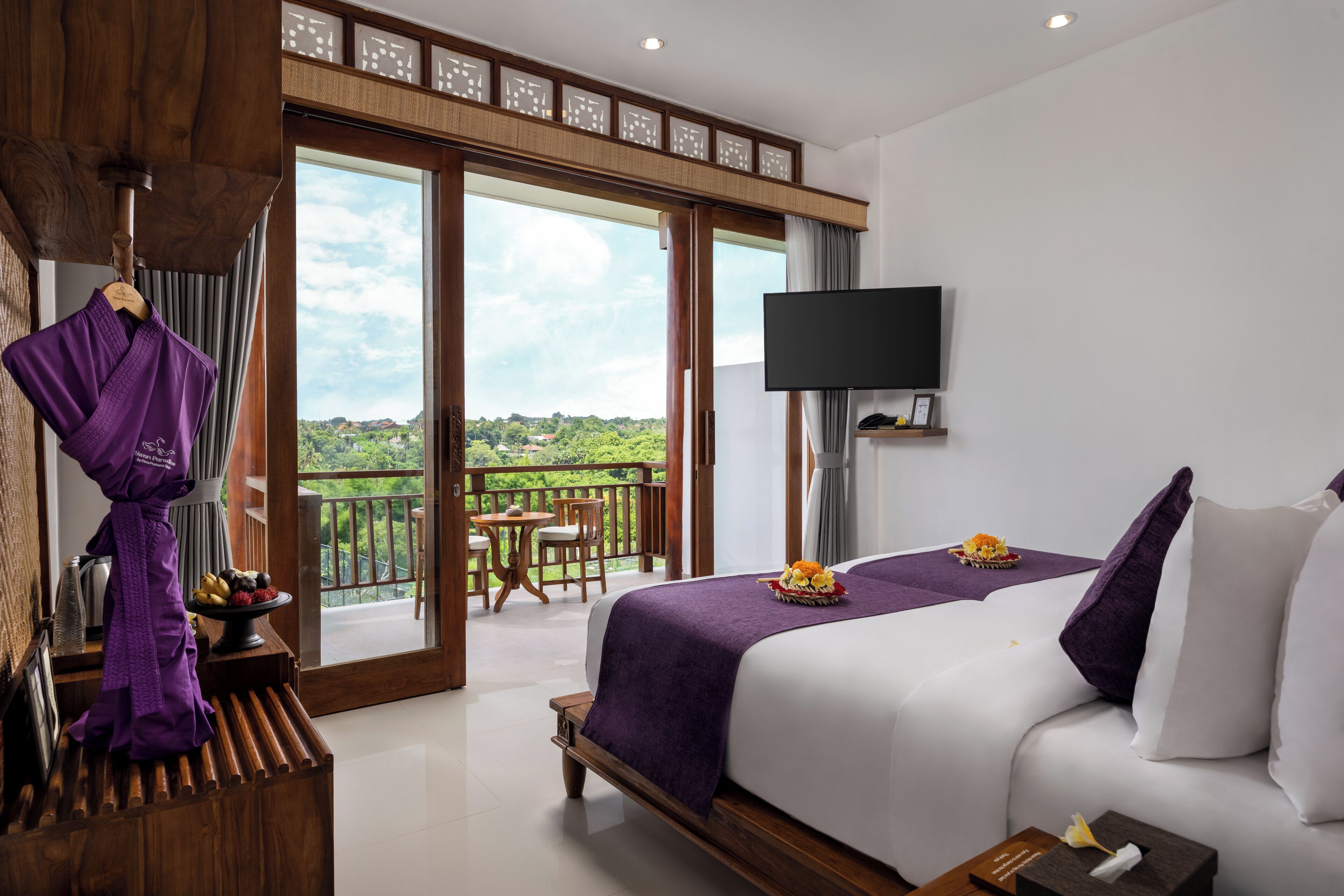 A hotel room with a large bed, a TV, a balcony with a view, and a robe rack.