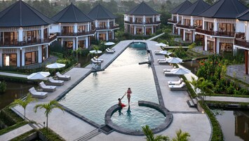 Un resort con diversi edifici, una piscina centrale e lettini prendisole disposti attorno.