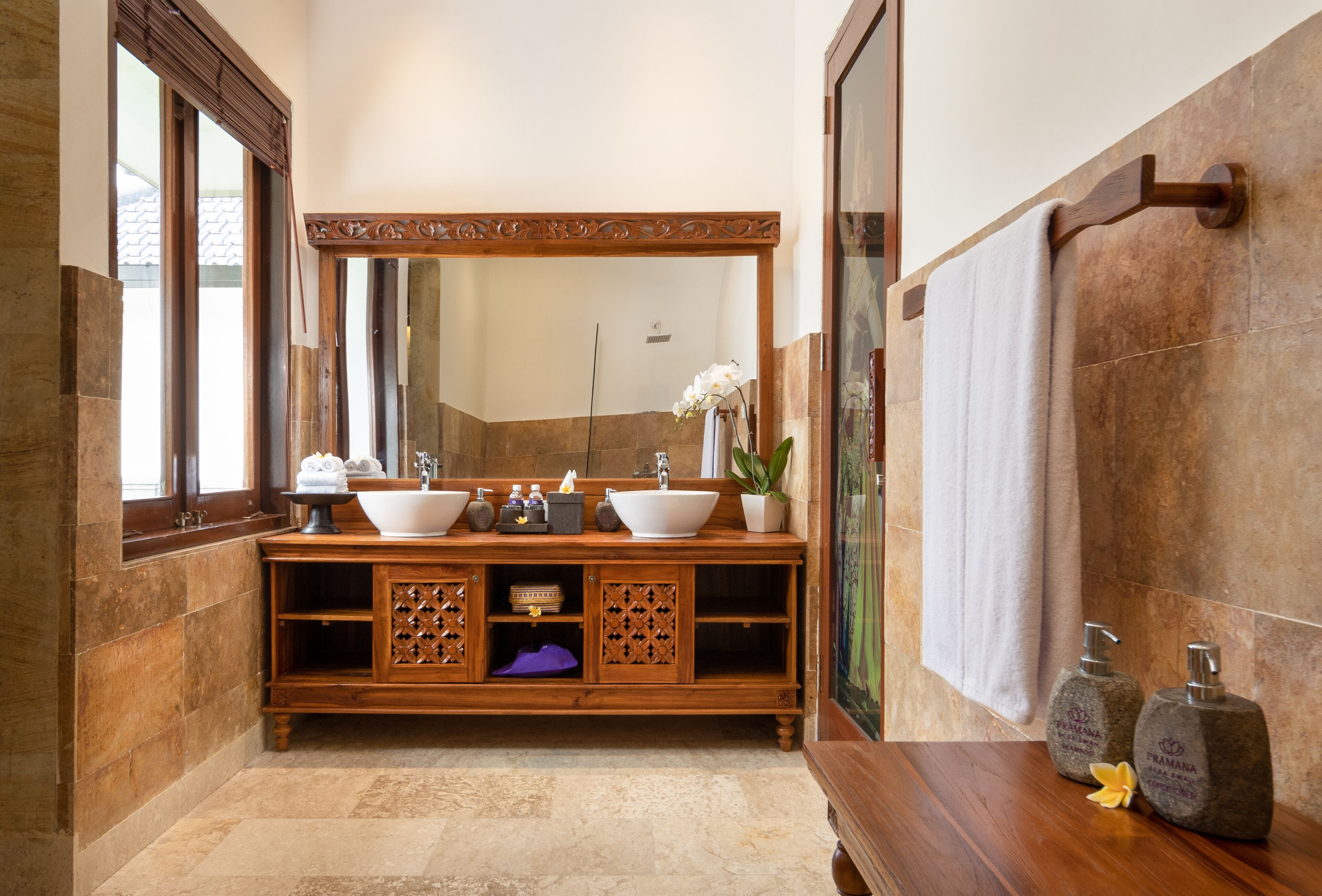 Une salle de bain avec un meuble-lavabo en bois, deux vasques, un grand miroir et un porte-serviettes.