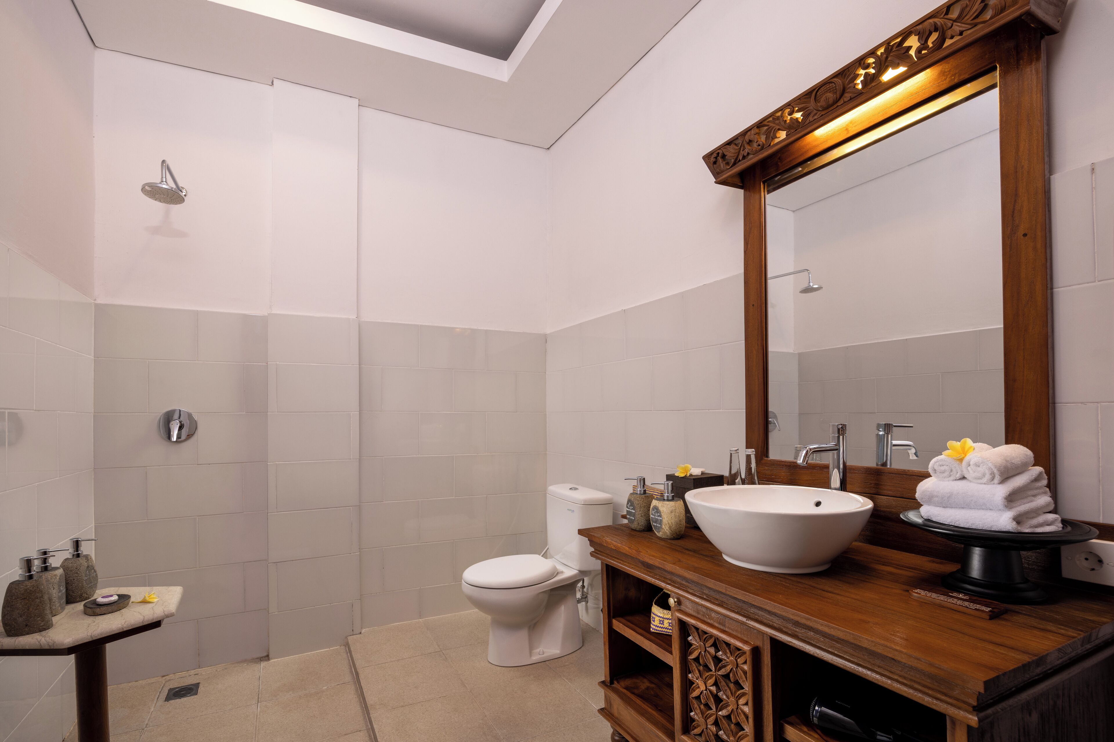 A modern bathroom with a skylight, a large mirror, a sink, and a toilet.