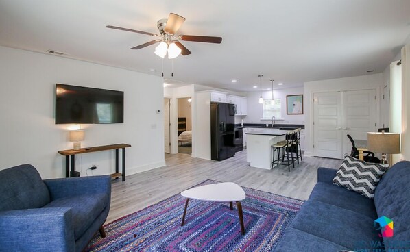 A modern living room with a ceiling fan, a TV, and two sofas.