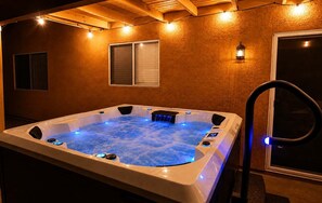 Un bain à remous avec un plafond en bois et des lampes fixées au mur.