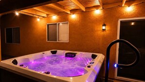 Un jacuzzi con iluminación integrada, una ventana y un aplique en la pared.