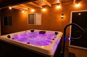 A hot tub with built-in lighting, a window, and a wall-mounted light fixture.