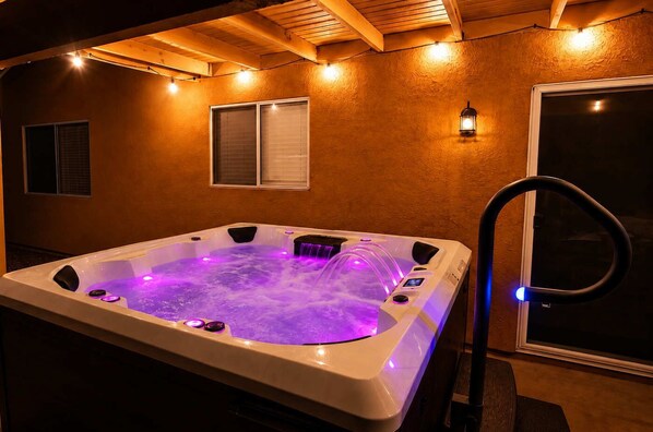 A hot tub with built-in lighting, a window, and a wall-mounted light fixture.