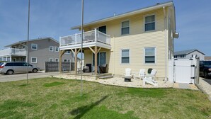 A two-story house with a balcony, a fenced yard, and a parked car. - Brigantine Condo w/ Gas Grill - Walk to Beach! (Brigantine)
