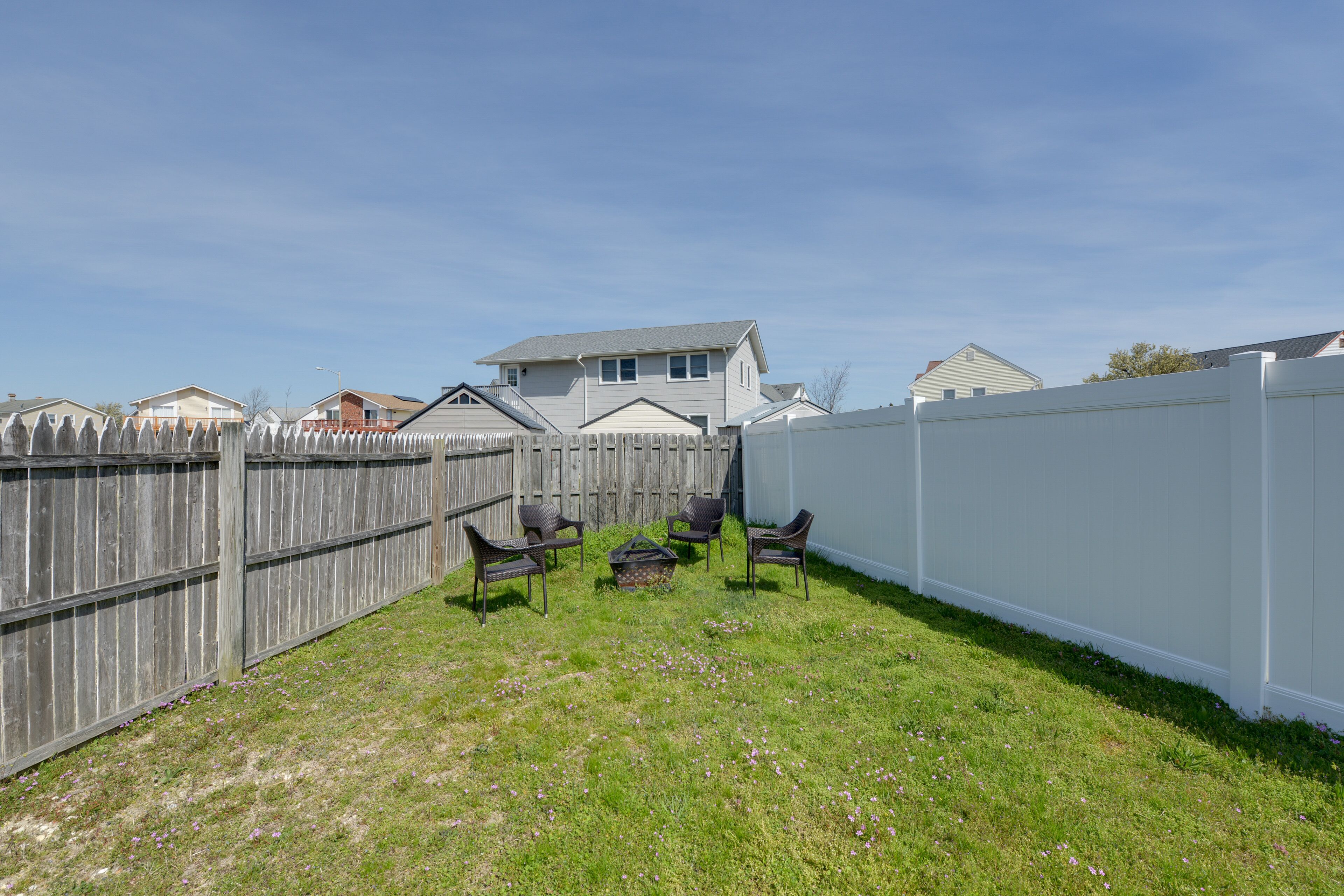 A fenced backyard with a grassy area and four chairs.