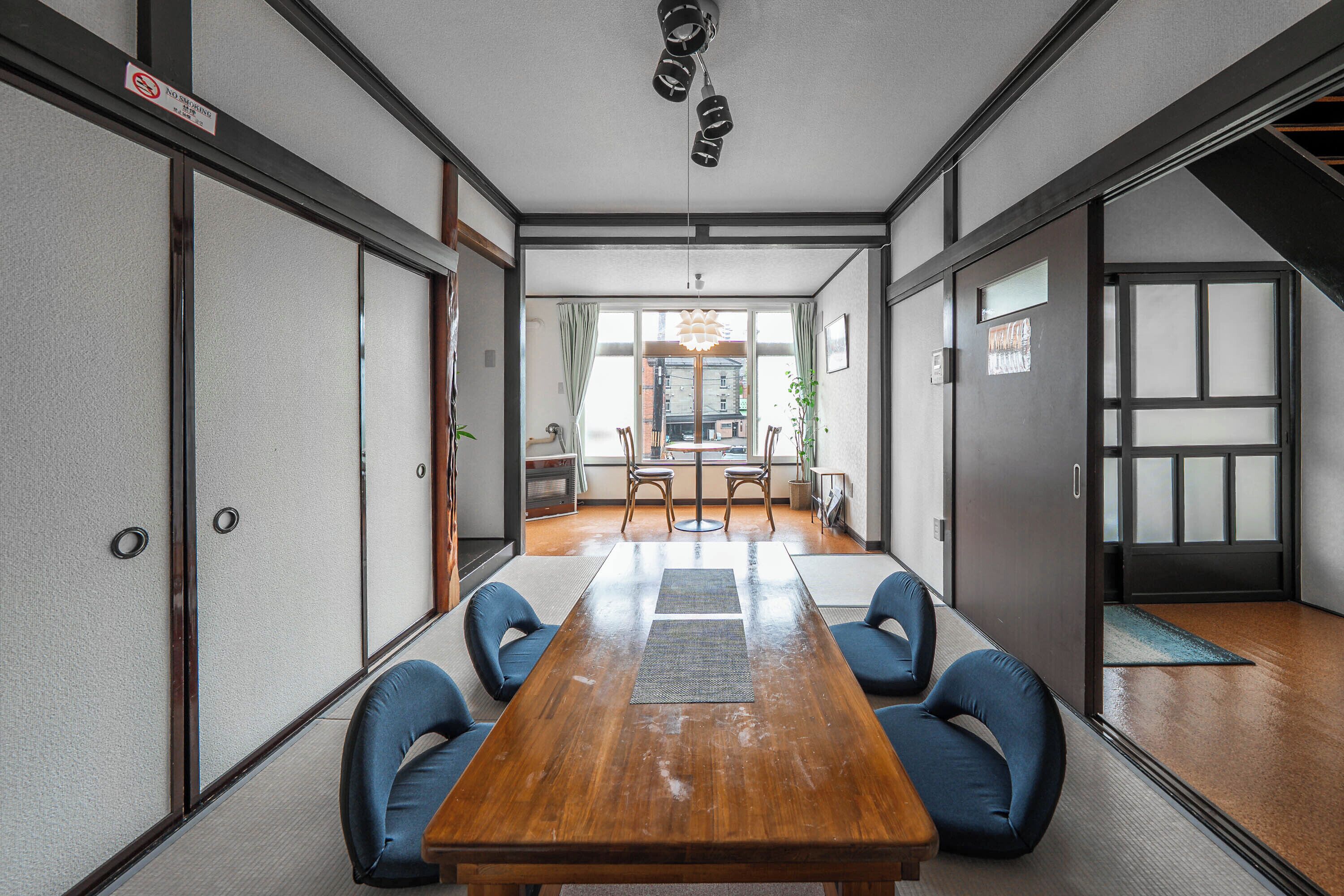 Une salle de réunion de style japonais traditionnel, avec des tatamis, une table en bois et des chaises rembourrées bleues.