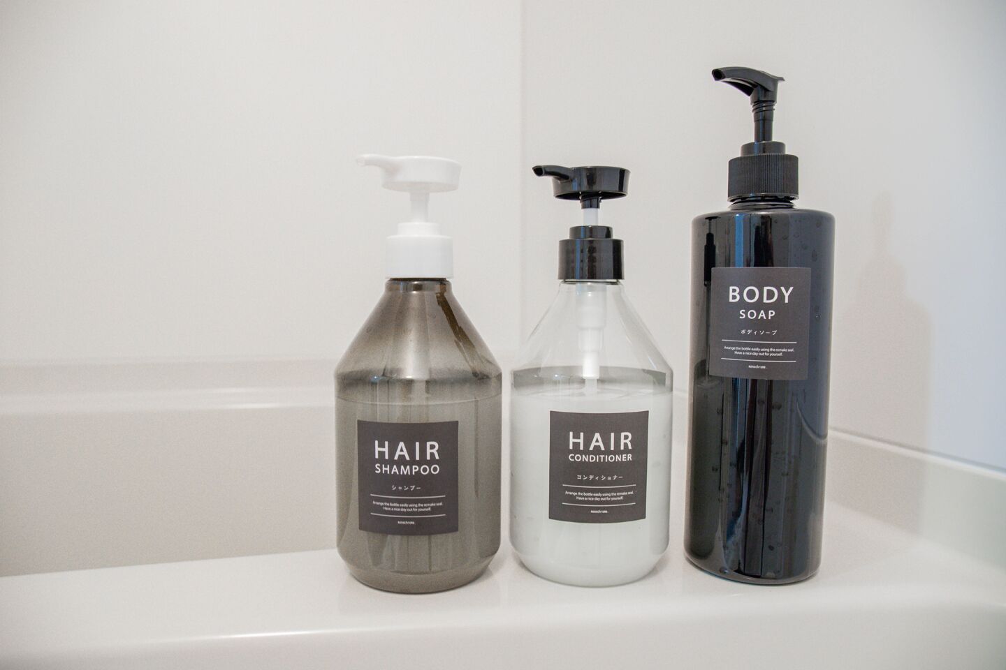 Three bottles of hair care products on a white shelf.