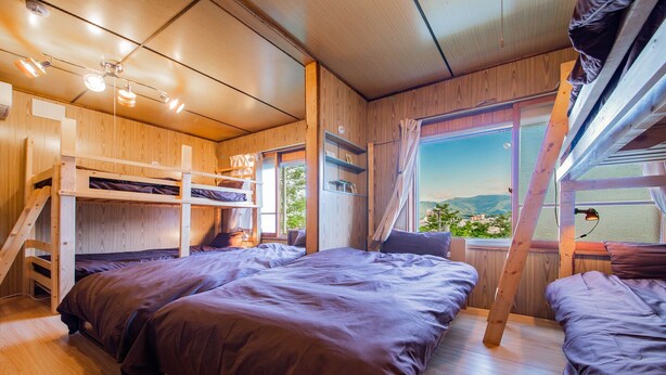 Una habitación con literas, una ventana con vistas y paredes de madera.