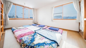 Ein Schlafzimmer mit einem großen Bett, zwei Fenstern, einer Deckenleuchte und Holzboden.